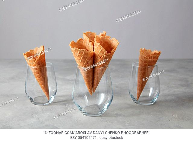 A glass vases with crispy wafer cones for sweet sorbet on a gray stone table, place for text. Spring or summer food concept