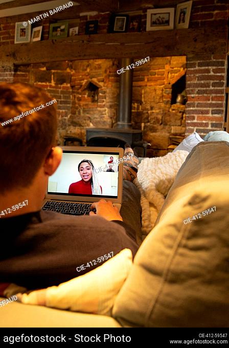 Man on sofa video conferencing with colleagues on laptop screen