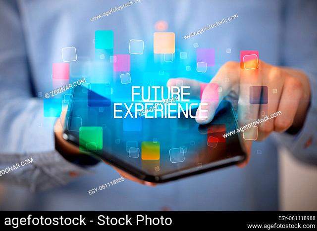 Young man holding a foldable smartphone with FUTURE EXPERIENCE inscription, educational concept