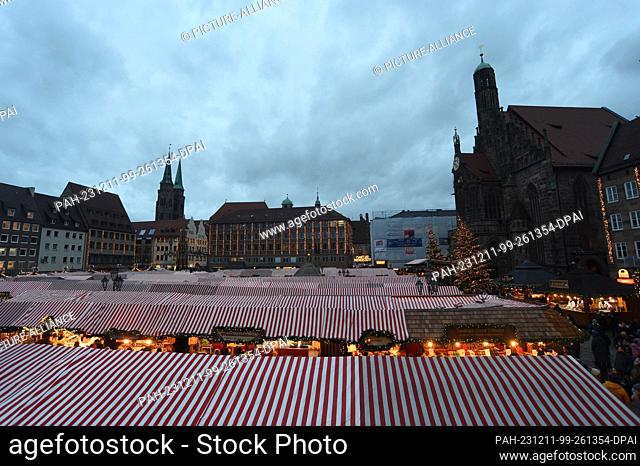11 December 2023, Bavaria, Nuremberg: Dark clouds hang over the striped roofs of the stalls at Nuremberg's Christkindlesmarkt