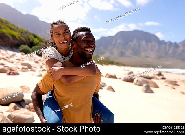 African american couple piggybacking on a beach by the sea
