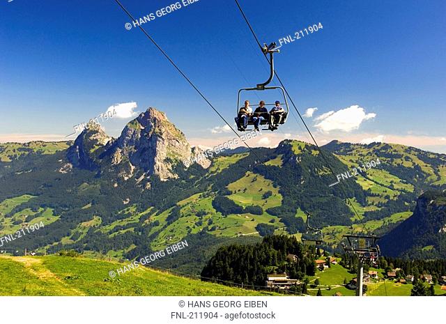 Tourists on ski lifts at mountainous landscape, Switzerland