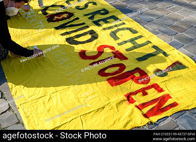 31 March 2021, Saxony-Anhalt, Magdeburg: A participant in a ""No Covid"" rally writes ""Enough!"" on a cloth in Cathedral Square. Covid Stop Effective
