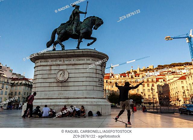 Young people skate boarding next to equestrian statue of King John I in the Praça da Figueira, Lisbon, Portugal