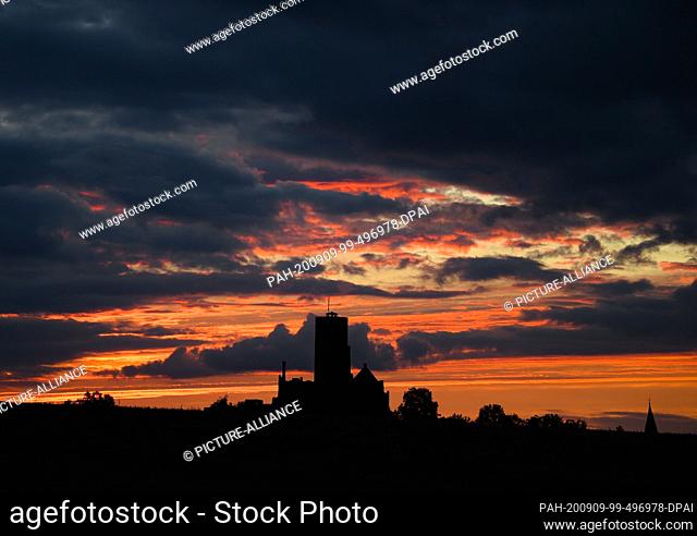 09 September 2020, Hessen, Münzenberg: The evening sky is coloured red-orange at sunset behind Burg Münzenberg in the Wetterau. Photo: Arne Dedert/dpa