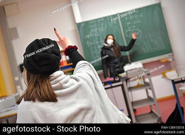 School lessons in times of the coronavirus pandemic. Teacher stands at a blackboard, school blackboard - a student sits on her seat and listens to the lesson