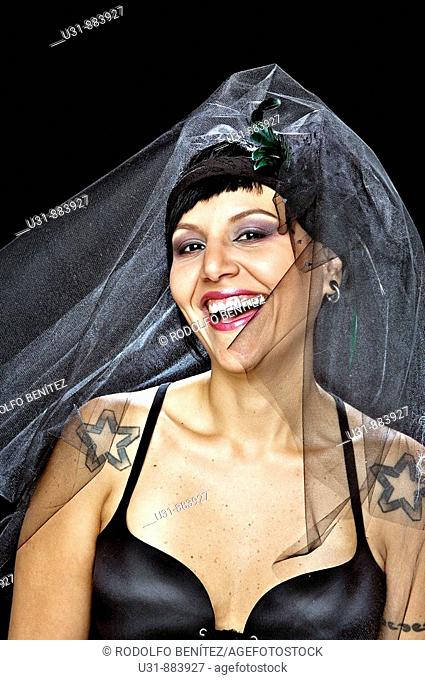 Punk Bride in her late 20s in a studio setting wearing a black wedding dress smiles