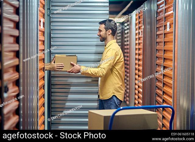 Side view of a joyous worker standing before the open shipping container in the warehouse