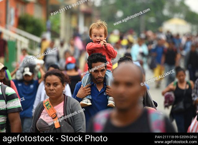 18 November 2021, Mexico, Veracruz: A man carries a young boy on his shoulders as he continues the march toward the U.S. border along with scores of migrants...