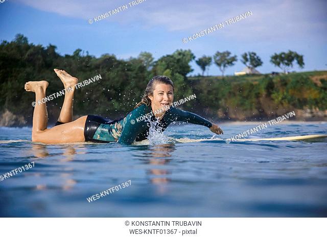 Indonesia, Bali, Balangan beach, female surfer lying on surfboard