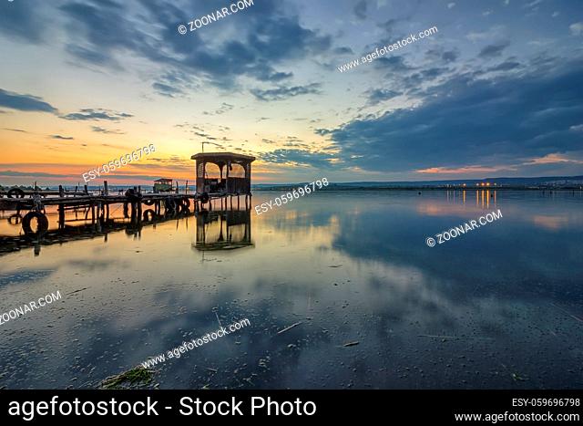 Exciting long exposure landscape on a lake with a wooden pier and gazebo in the end
