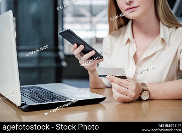Young female professional using credit card to do online shopping at cafe