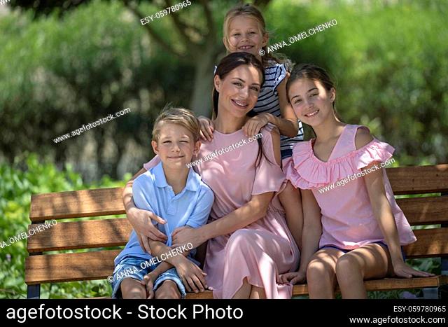 Happy Mother and Her Three Precious Kids Spending Weekend Together Outdoors. Family Time in City Park on Summer Day. Love Concept