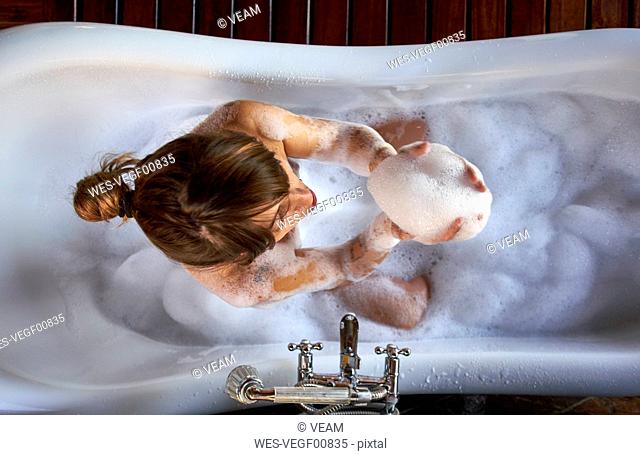 Woman playing with the foam in a bathtub, from above