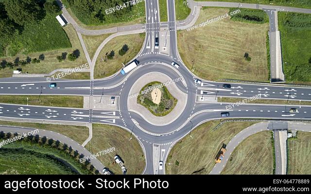 Top down aerial view of a traffic roundabout on a main road in an urban area