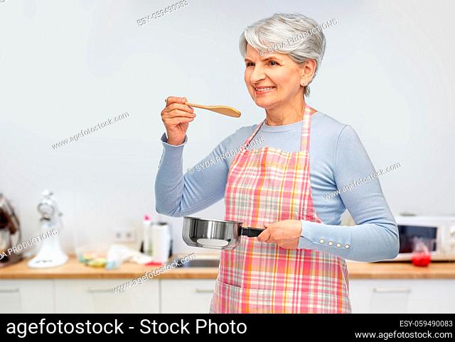 senior woman in apron with pot cooking food
