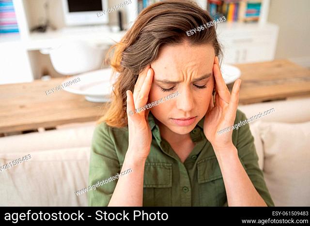 Woman with headache touching her head at home