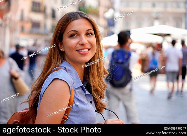 Portrait of attractive tourist woman looking back with defocused people on the background. Copy space