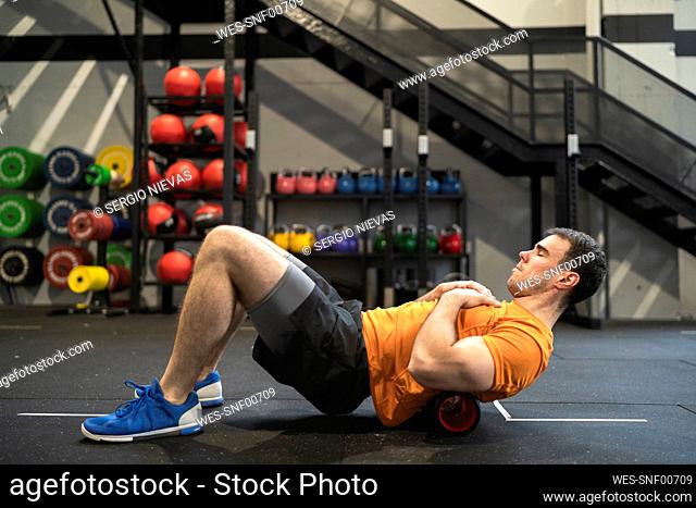 Sportsman practicing with pilates rolls in gym