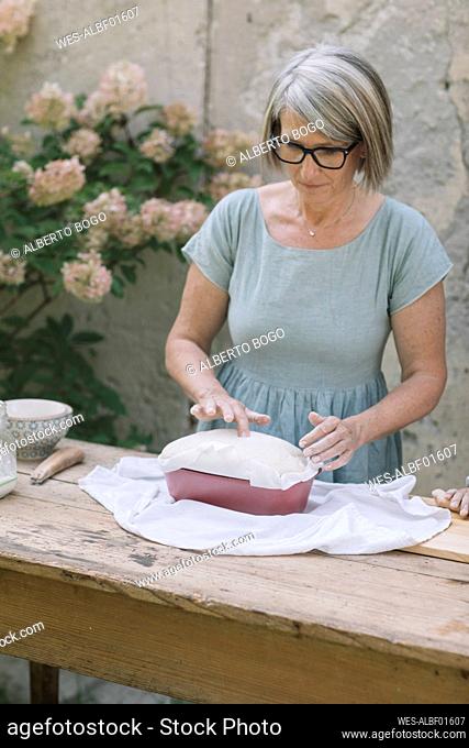 Mature woman with baked bread at back yard
