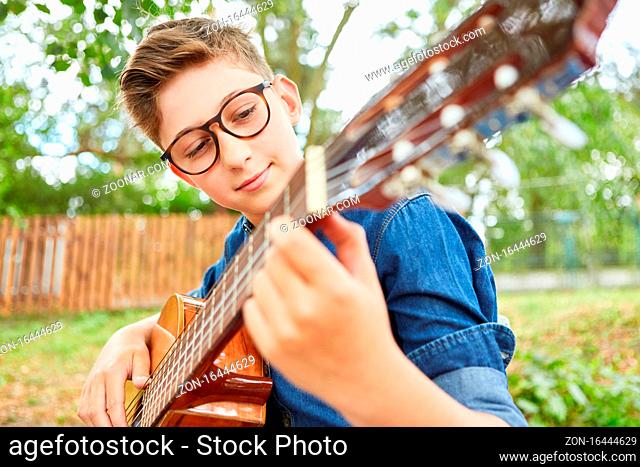 Kind beim Gitarre spielen in einem Gitarrenkurs im Sommercamp oder bei Talentshow