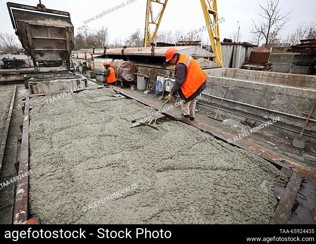 RUSSIA, ZAPOROZHYE REGION - DECEMBER 19, 2023: Employees level fresh concrete at a plant of reinforced concrete structures in the city of Berdyansk