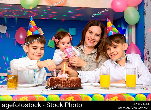 Children on a family birthday put candles in a birthday cake