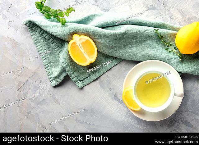 A cup of green tea with lemons and herbs, shot from above with copy space