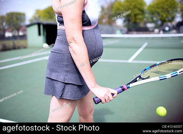 Pregnant woman playing tennis on tennis court