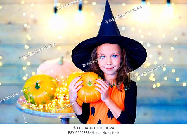 Happy witch children during Halloween party playing around the table with pumpkins