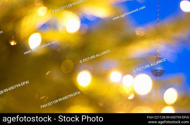 27 November 2022, Berlin: Between the branches of a fir tree decorated with lights, the sphere of the TV tower can be seen. Photo: Paul Zinken/dpa
