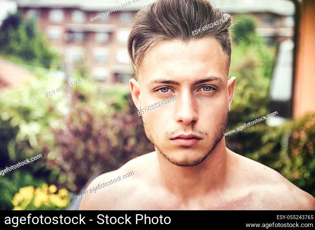 Headshot of handsome shirtless young man outdoor, looking at camera