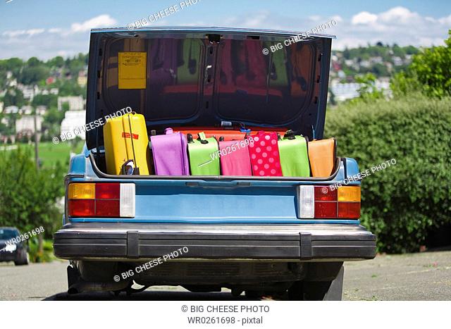 Car trunk loaded with colorful suitcases