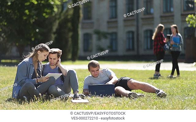 College students using laptop and tablet on lawn