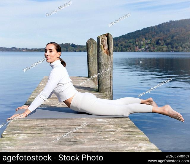 Active woman doing cobra pose on jetty