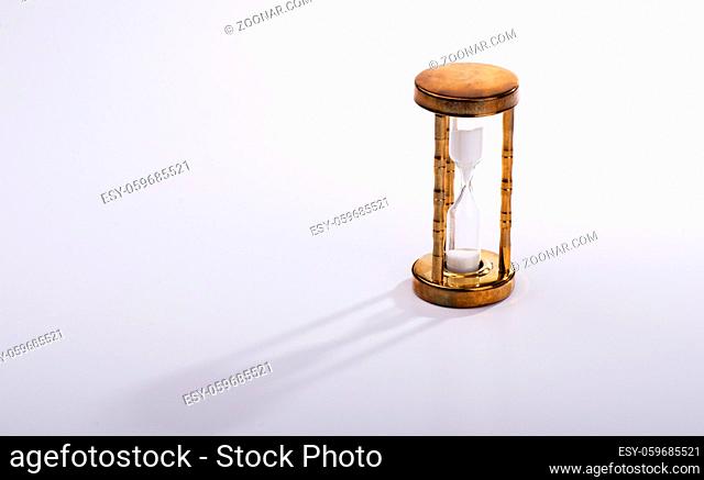 Vintage hourglass on gray background with long shadow