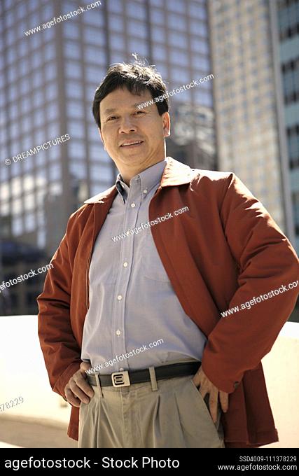 Asian man with hands on hips in urban area