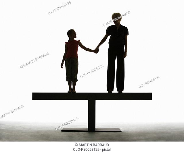 Woman and young girl holding hands on a plank