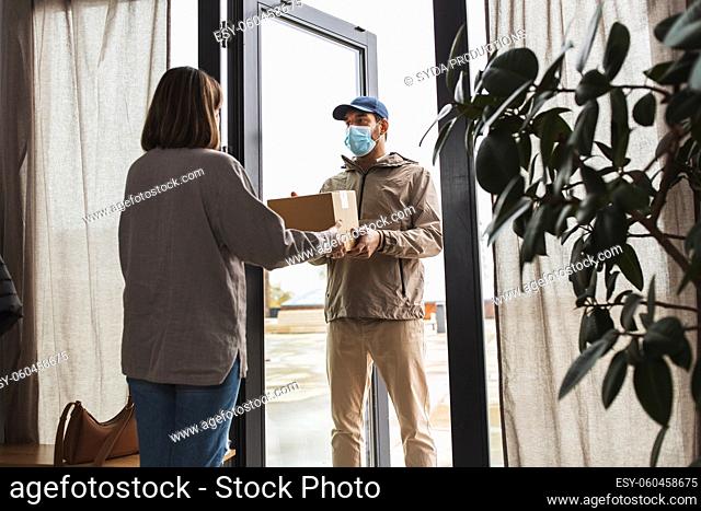 delivery man in mask giving parcel to customer