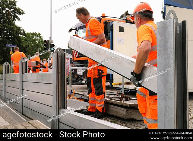 21 July 2021, Saxony, Dresden: Employees of the city of Dresden set up a mobile flood protection system on Schlachthofstraße for a test run