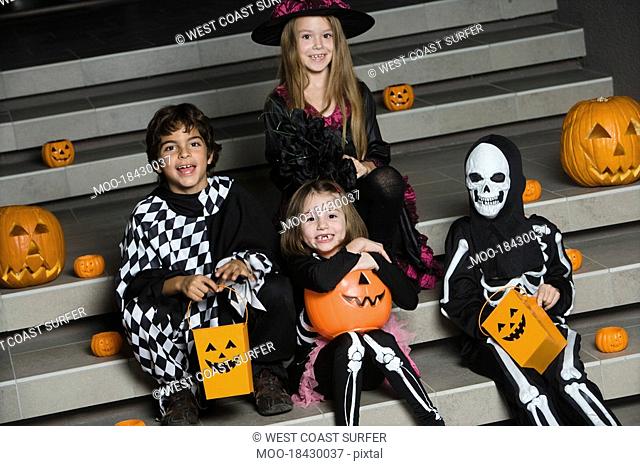 Portrait of boys and girls 7-9 wearing Halloween costumes on steps