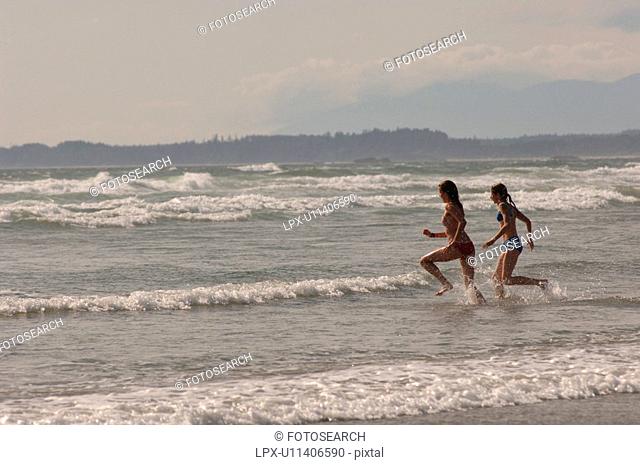 Two women running into ocean