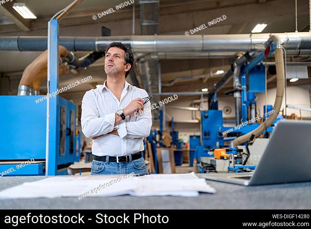 Portrait of carpenter examining documents in production hall