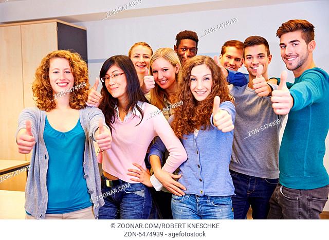 Jugendliche glückliche Gruppe im Klassenzimmer hält die Daumen hoch