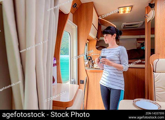 Woman in the interior of a camper RV motorhome with a cup of coffee looking at nature