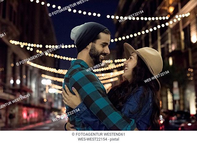 Happy young couple hugging on the steet at night