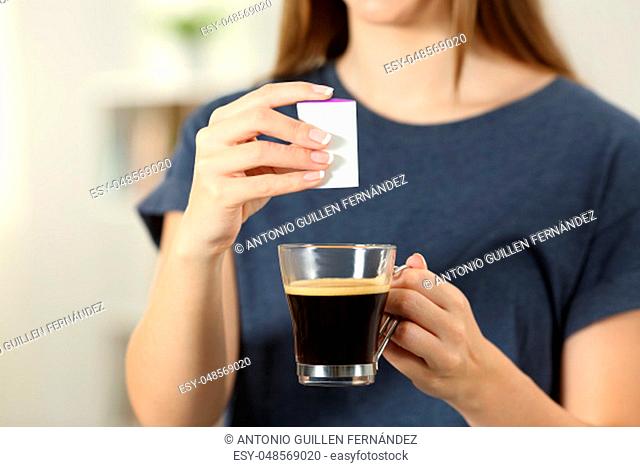 Front view close up of a woman hands throwing saccharin into a coffee cup at home