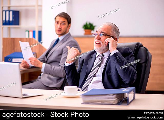 Old male boss and young male assistant in the office