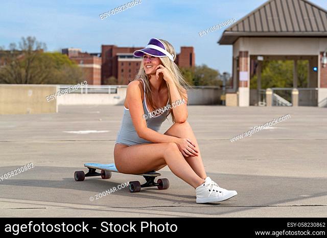 A gorgeous young blonde model enjoys a summer day with her skateboard