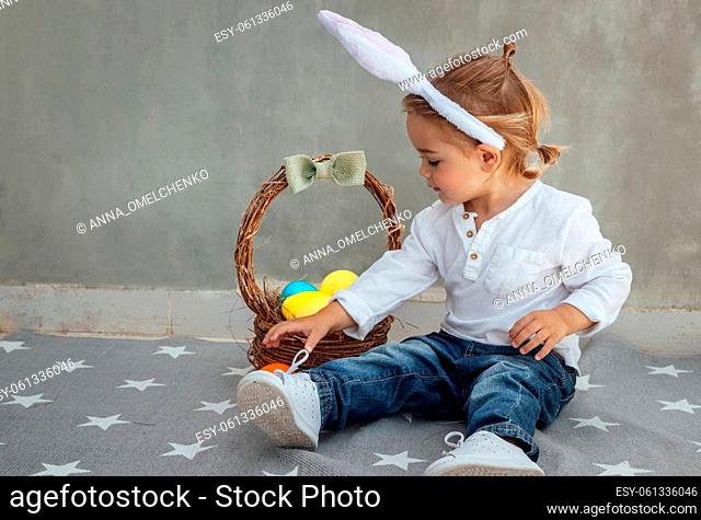 Cute Little Boy Dressed as a Bunny with Basket Full of Colorful Easter Eggs. Egg Hunting. Happy Christian Spring Holiday